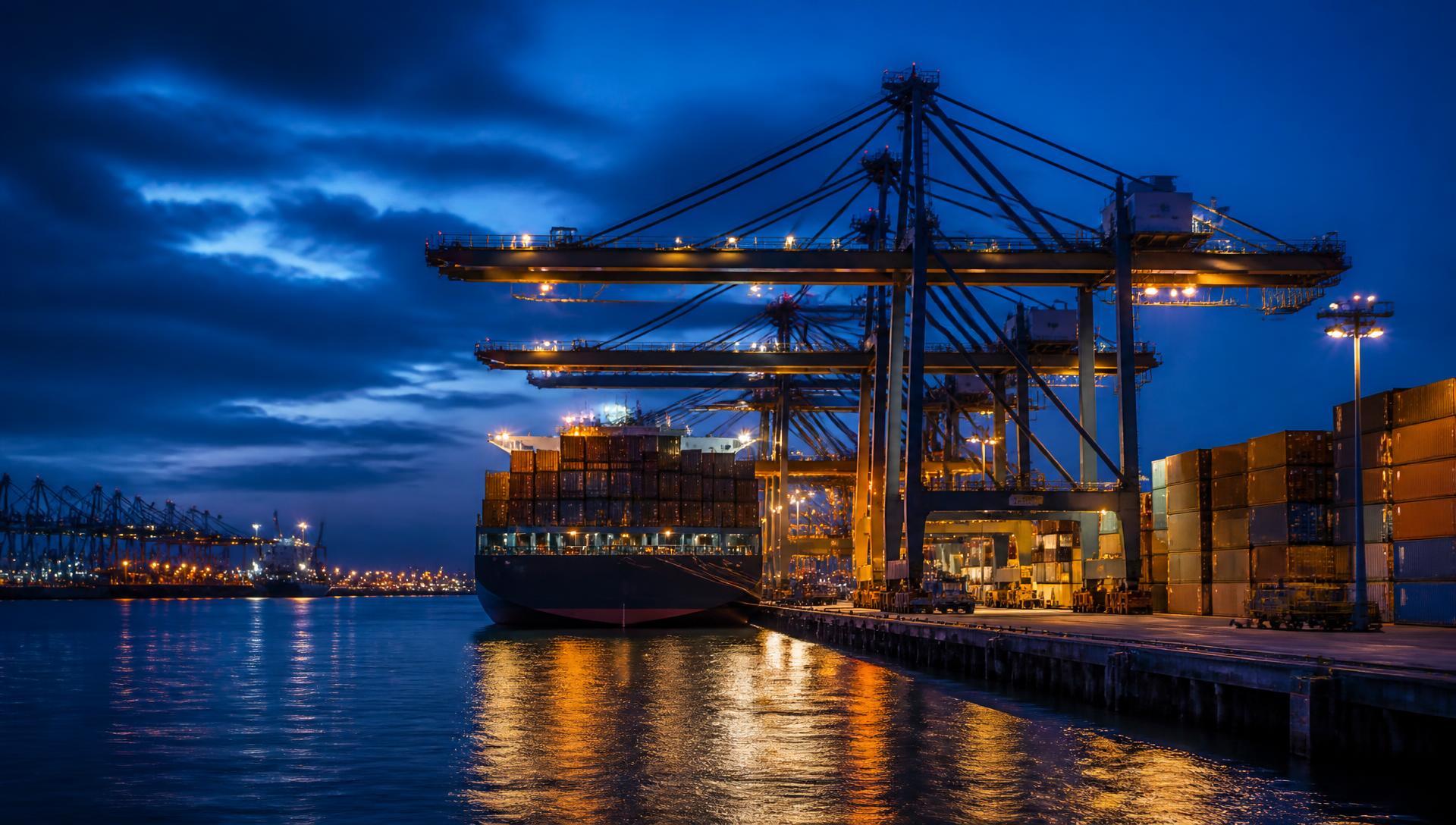 Container ship being loaded by gantry cranes at an international port at dusk